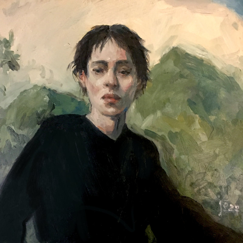 Androgynous person looking head on with mountains behind.